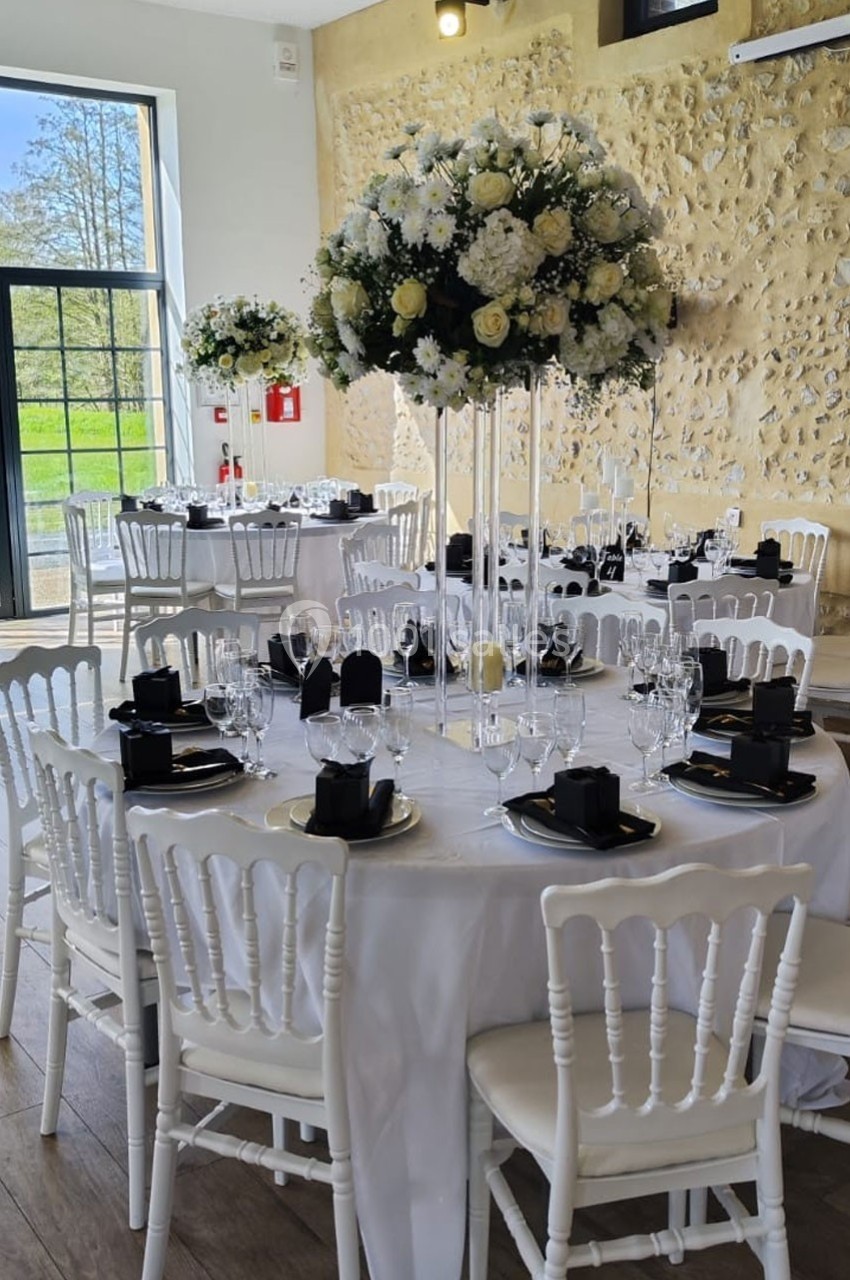 Location salle Sylvains-les-Moulins (Eure) - Domaine de Coulonge #58 Salle de réception décorée avec des tables rondes, nappes blanches, chaises blanches et centres de table fleuris.