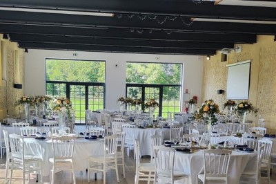 Miniature Location salle Sylvains-les-Moulins (Eure) - Domaine de Coulonge #15 Salle de réception décorée avec des tables rondes, nappes blanches, chaises blanches et centres de table fleuris.