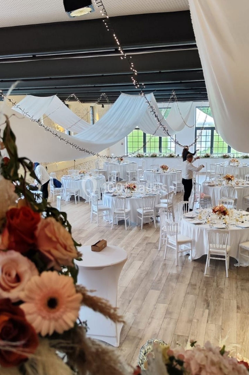 Location salle Sylvains-les-Moulins (Eure) - Domaine de Coulonge #6 Salle de réception décorée avec des tables rondes, nappes blanches, fleurs et guirlandes lumineuses suspendues.