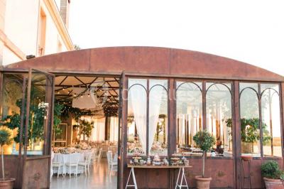 Miniature Location salle Lançon-Provence (Bouches-du-Rhône) - La Bastide d'Astres #7 Vue d'une terrasse avec parasols et piscine, encadrée par des haies sombres et un ciel dégagé en arrière-plan.