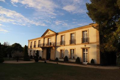 Miniature Location salle Lançon-Provence (Bouches-du-Rhône) - La Bastide d'Astres #14 Vue d'une terrasse avec parasols et piscine, encadrée par des haies sombres et un ciel dégagé en arrière-plan.