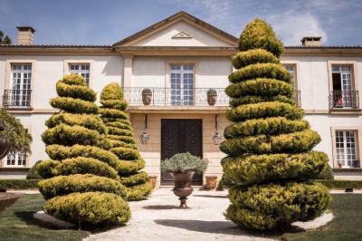 Miniature Location salle Lançon-Provence (Bouches-du-Rhône) - La Bastide d'Astres #18 Vue d'une terrasse avec parasols et piscine, encadrée par des haies sombres et un ciel dégagé en arrière-plan.