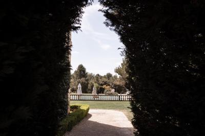 Miniature Location salle Lançon-Provence (Bouches-du-Rhône) - La Bastide d'Astres #21 Vue d'une terrasse avec parasols et piscine, encadrée par des haies sombres et un ciel dégagé en arrière-plan.