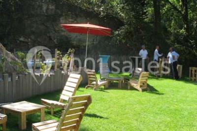 Petit ruisseau bordé de végétation avec des tentes blanches installées pour un événement en arrière-plan.