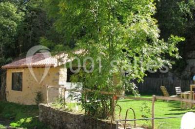 Petit ruisseau bordé de végétation avec des tentes blanches installées pour un événement en arrière-plan.