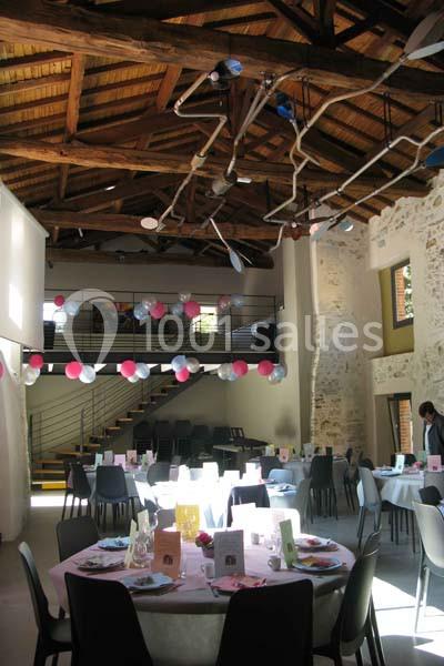 Salle de réception décorée avec des ballons et des tables dressées pour un événement festif.