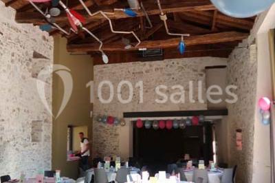 Petit ruisseau bordé de végétation avec des tentes blanches installées pour un événement en arrière-plan.