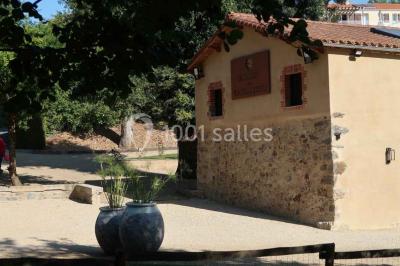 Petit ruisseau bordé de végétation avec des tentes blanches installées pour un événement en arrière-plan.