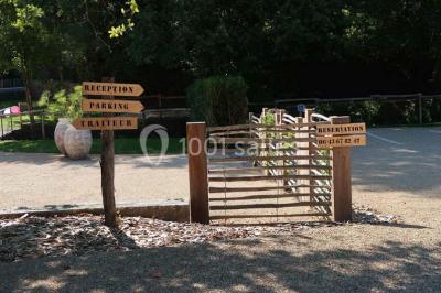 Petit ruisseau bordé de végétation avec des tentes blanches installées pour un événement en arrière-plan.