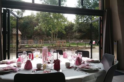 Petit ruisseau bordé de végétation avec des tentes blanches installées pour un événement en arrière-plan.