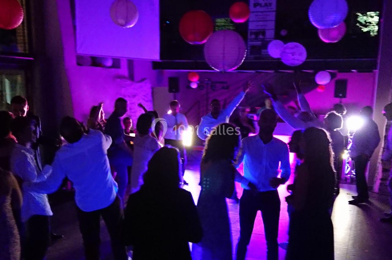 Groupe de personnes dansant dans une salle faiblement éclairée, décorée de lanternes suspendues.