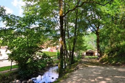 Petit ruisseau bordé de végétation avec des tentes blanches installées pour un événement en arrière-plan.