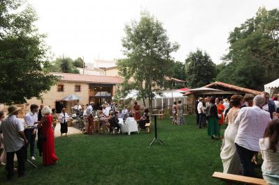 Petit ruisseau bordé de végétation avec des tentes blanches installées pour un événement en arrière-plan.