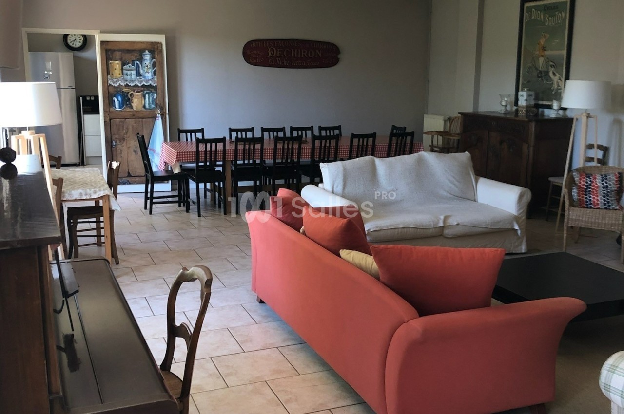 Salon spacieux avec canapés, table à manger longue, chaises noires et décoration murale dans un intérieur lumineux.
