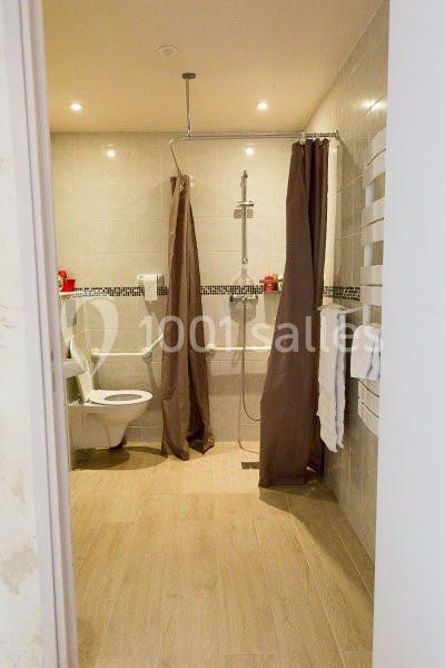 Salle de bain accessible avec douche à l'italienne, barres d'appui, rideaux et toilettes adaptées.