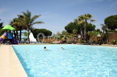 Miniature Location salle Le Barcarès (Pyrénées-Orientales) - Nai'a Village #6 Terrasse en bois avec pergola, mobilier de jardin et façade vitrée donnant sur un espace intérieur moderne.
