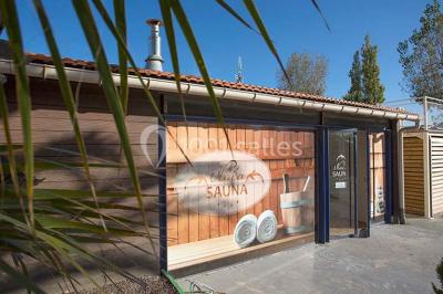 Miniature Location salle Le Barcarès (Pyrénées-Orientales) - Nai'a Village #9 Terrasse en bois avec pergola, mobilier de jardin et façade vitrée donnant sur un espace intérieur moderne.