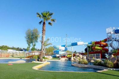Miniature Location salle Le Barcarès (Pyrénées-Orientales) - Nai'a Village #4 Terrasse en bois avec pergola, mobilier de jardin et façade vitrée donnant sur un espace intérieur moderne.