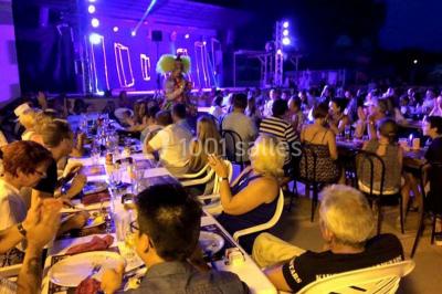 Miniature Location salle Le Barcarès (Pyrénées-Orientales) - Nai'a Village #7 Terrasse en bois avec pergola, mobilier de jardin et façade vitrée donnant sur un espace intérieur moderne.