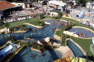 Miniature Location salle Le Barcarès (Pyrénées-Orientales) - Nai'a Village #13 Terrasse en bois avec pergola, mobilier de jardin et façade vitrée donnant sur un espace intérieur moderne.