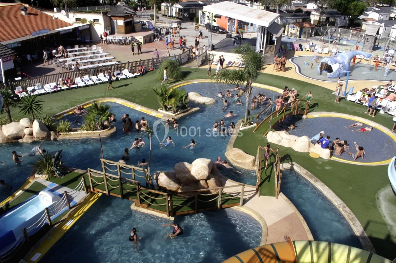 Vue aérienne d'un parc aquatique avec piscines, toboggans, ponts en bois et visiteurs profitant des activités.