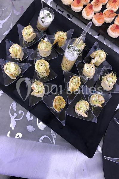 Plateau de verrines et amuse-bouches variés disposés sur un support noir, décorés de pousses et herbes fraîches.