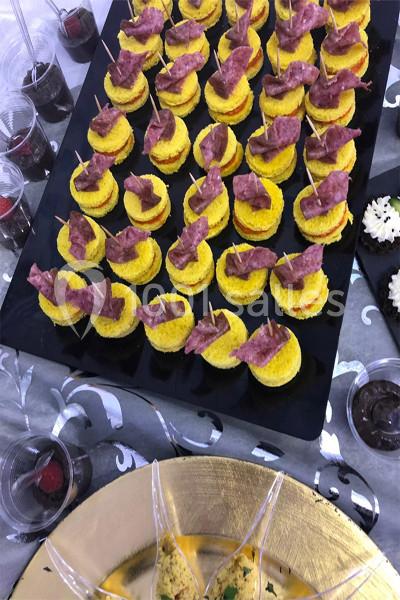 Plateau de bouchées apéritives composées de tranches de pain, fromage et charcuterie, disposées sur des pics en bois.