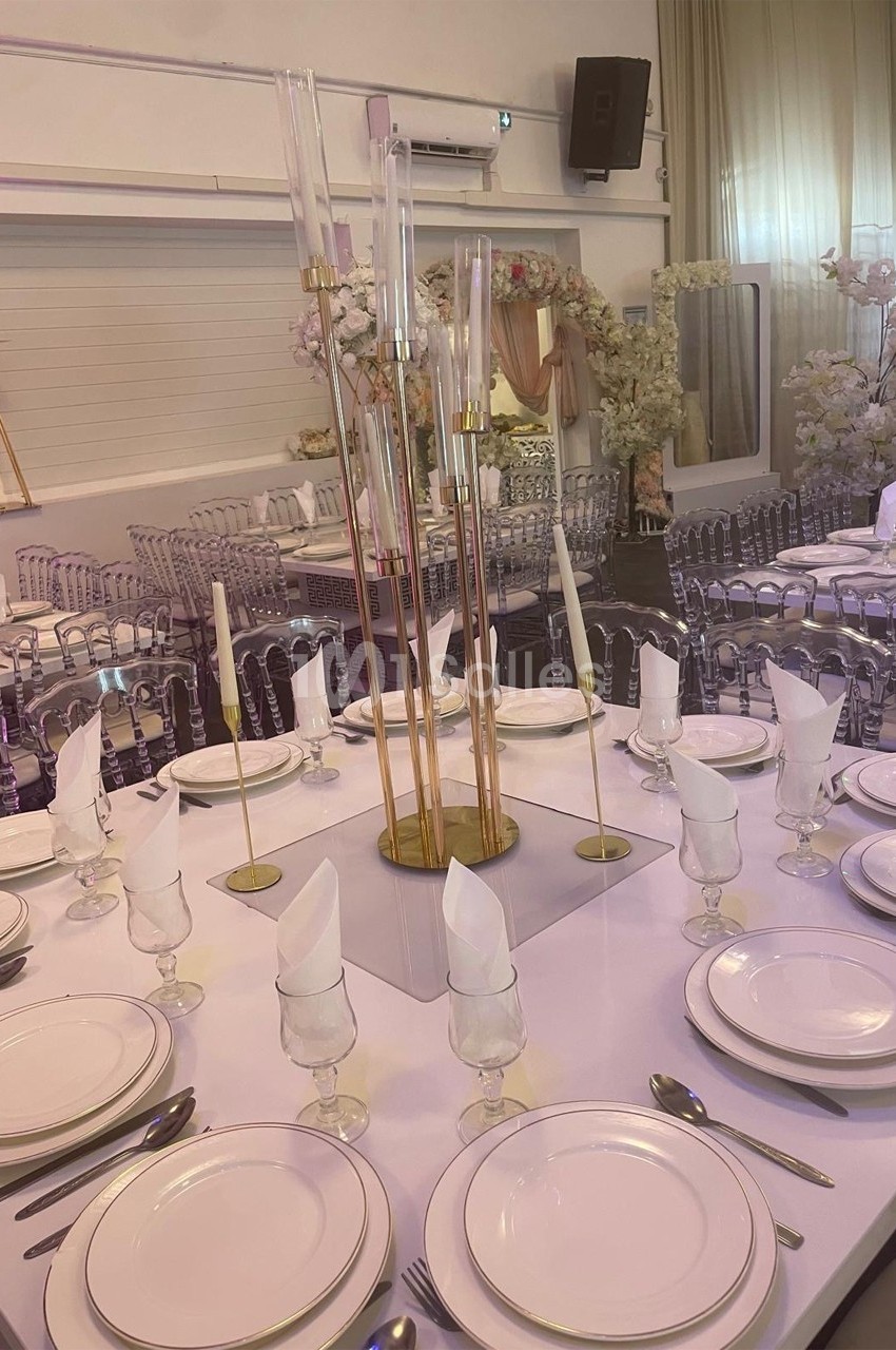Table élégamment dressée avec vaisselle blanche, serviettes pliées et centre de table décoratif dans une salle ornée de…