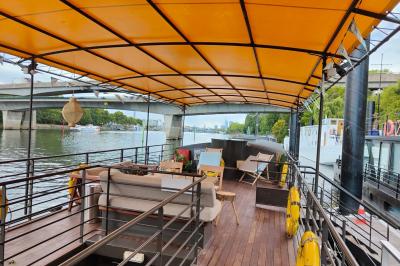 Miniature Location salle Suresnes (Hauts-de-Seine) - La Petite Péniche du 92 #2 Cuisine étroite avec plaques de cuisson, étagères remplies de cartons et vaisselle, et un réfrigérateur en acier inoxydable.