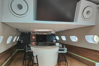 Miniature Location salle Suresnes (Hauts-de-Seine) - La Petite Péniche du 92 #4 Cuisine étroite avec plaques de cuisson, étagères remplies de cartons et vaisselle, et un réfrigérateur en acier inoxydable.