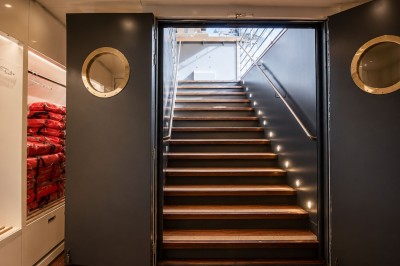 Miniature Location salle Suresnes (Hauts-de-Seine) - La Petite Péniche du 92 #11 Escalier en bois éclairé menant à l'extérieur, encadré par des portes grises avec hublots circulaires.