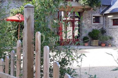 Miniature Location salle Gouesnou (Finistère) - La Cour des Grands #4 Allée bordée de buis en pots et d'un mur en pierre, avec pelouse et arbres en arrière-plan.
