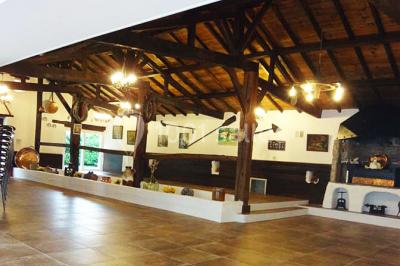 Un jardin verdoyant avec pelouse, arbres, arbustes et une charrette ancienne près d'un abri en bois.