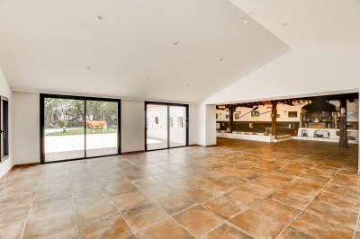 Un jardin verdoyant avec pelouse, arbres, arbustes et une charrette ancienne près d'un abri en bois.