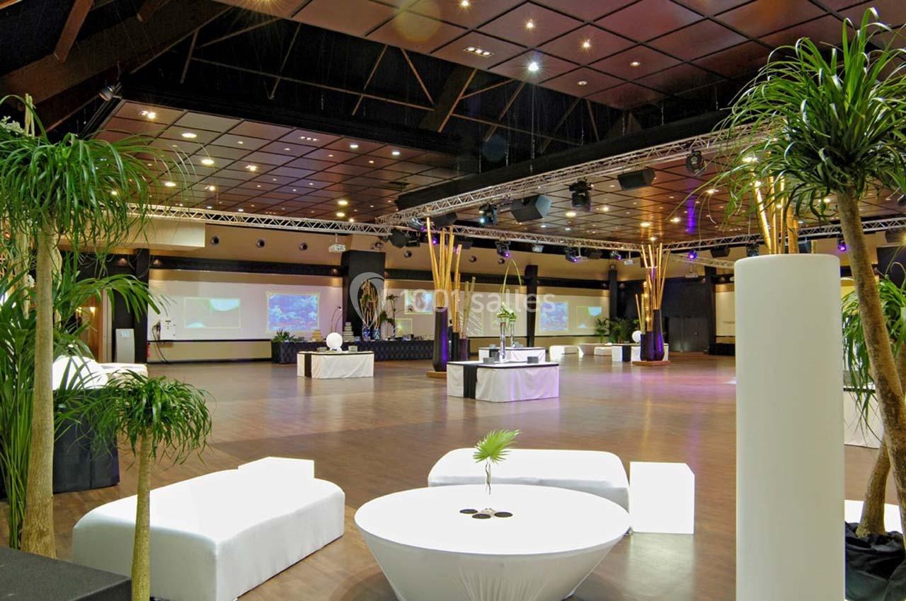 Salle spacieuse avec parquet, éclairage moderne, mobilier blanc et plantes décoratives.