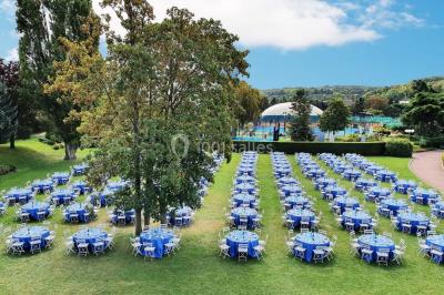 Miniature Location salle Le Port-Marly (Yvelines) - Les Pyramides #21 Tables rondes dressées avec nappes bleues alignées sur une pelouse, entourées d'arbres, avec un parc en arrière-plan.