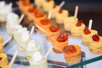 Dessert en forme de cœur au chocolat sur une assiette blanche, accompagné de coulis rouge et d'une verrine en arrière-plan.
