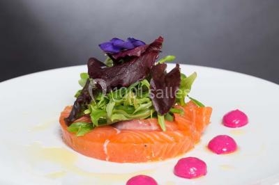 Dessert en forme de cœur au chocolat sur une assiette blanche, accompagné de coulis rouge et d'une verrine en arrière-plan.