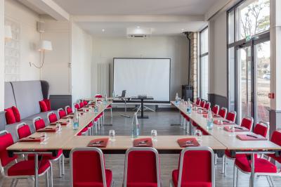 Dessert en forme de cœur au chocolat sur une assiette blanche, accompagné de coulis rouge et d'une verrine en arrière-plan.