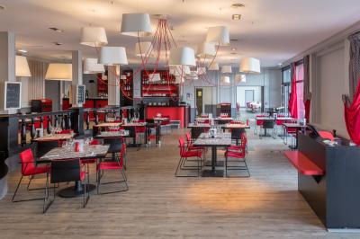Dessert en forme de cœur au chocolat sur une assiette blanche, accompagné de coulis rouge et d'une verrine en arrière-plan.