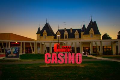 Dessert en forme de cœur au chocolat sur une assiette blanche, accompagné de coulis rouge et d'une verrine en arrière-plan.