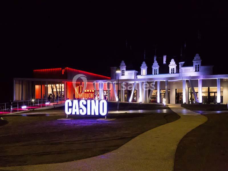 Location salle La Roche-Posay (Vienne) - Casino de la Roche Posay #3 Façade d'un casino éclairé la nuit avec enseigne lumineuse et bâtiment principal aux tons rouges et blancs.