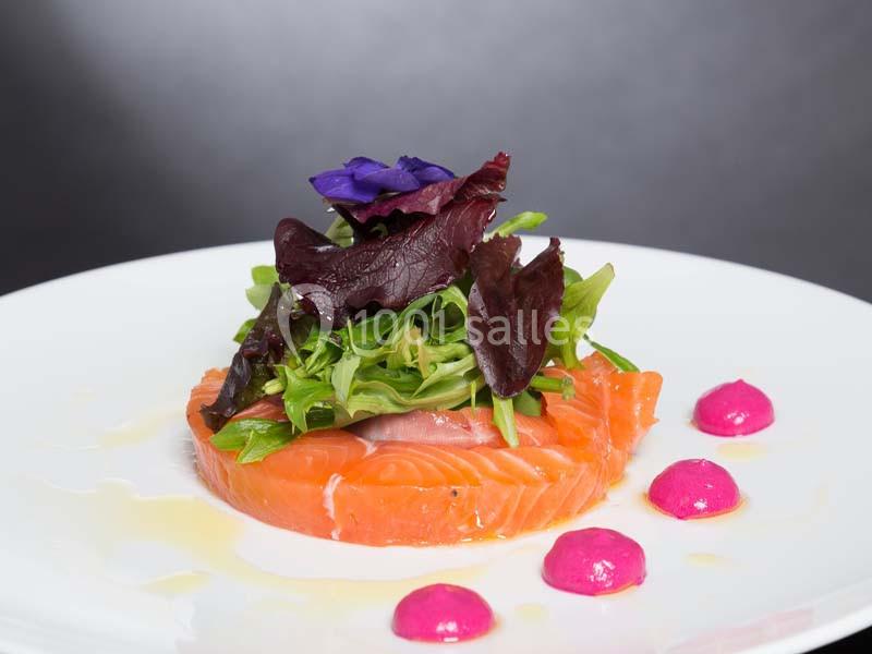 Location salle La Roche-Posay (Vienne) - Casino de la Roche Posay #12 Tranche de saumon cru garnie de salade verte, fleurs comestibles et points de sauce rose sur une assiette blanche.