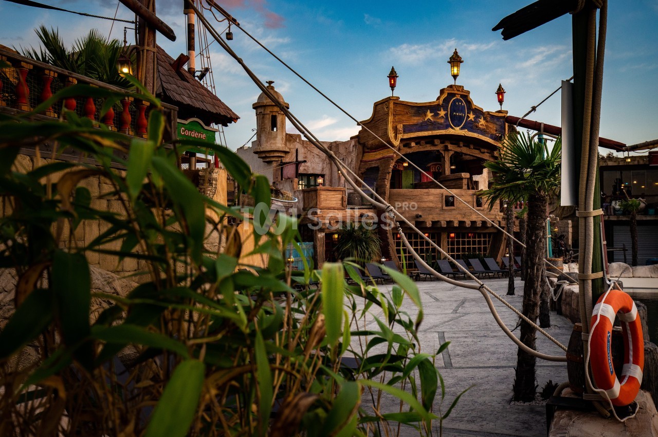 Façade d'un bâtiment à thème pirate avec des décorations en bois, des cordages et des plantes au premier plan.