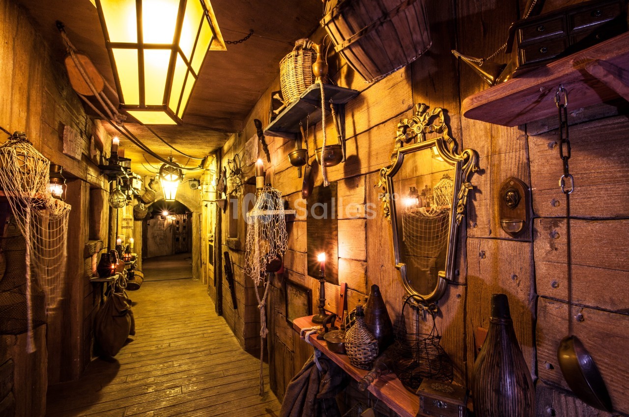 Couloir en bois décoré de lanternes, miroirs, filets et objets anciens, créant une ambiance rustique et chaleureuse.