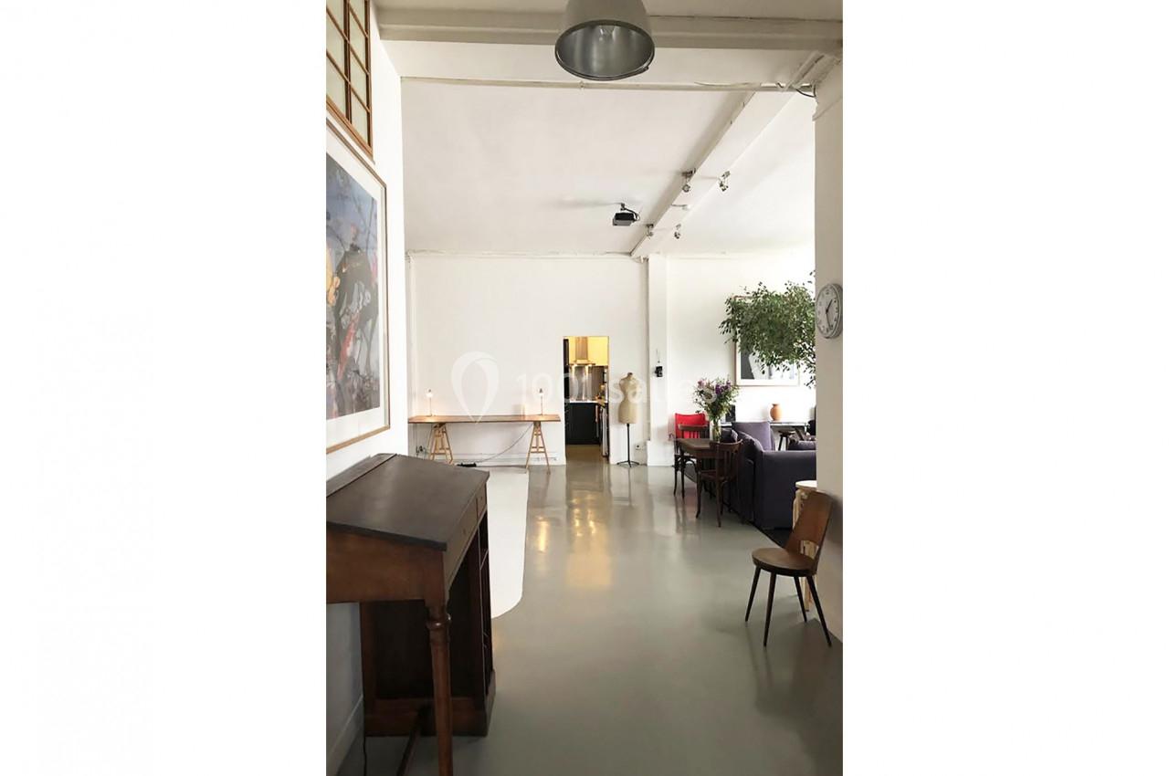 Intérieur lumineux avec mobilier minimaliste, plantes et un espace ouvert comprenant des tables et des chaises.