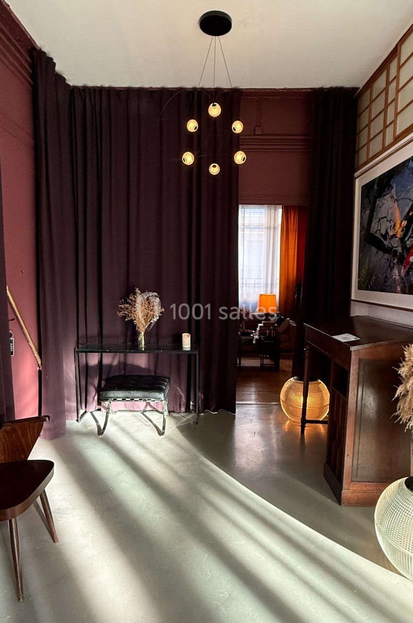 Location salle Paris 20 (Paris) - Studio 7 #25 Entrée décorée avec des rideaux violets, mobilier en bois, éclairage tamisé et éléments de décoration naturels.