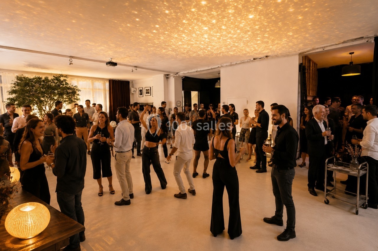 Location salle Paris 20 (Paris) - Studio 7 #34 Groupe de personnes discutant et dansant dans une salle lumineuse avec un éclairage chaleureux et une ambiance conviviale.