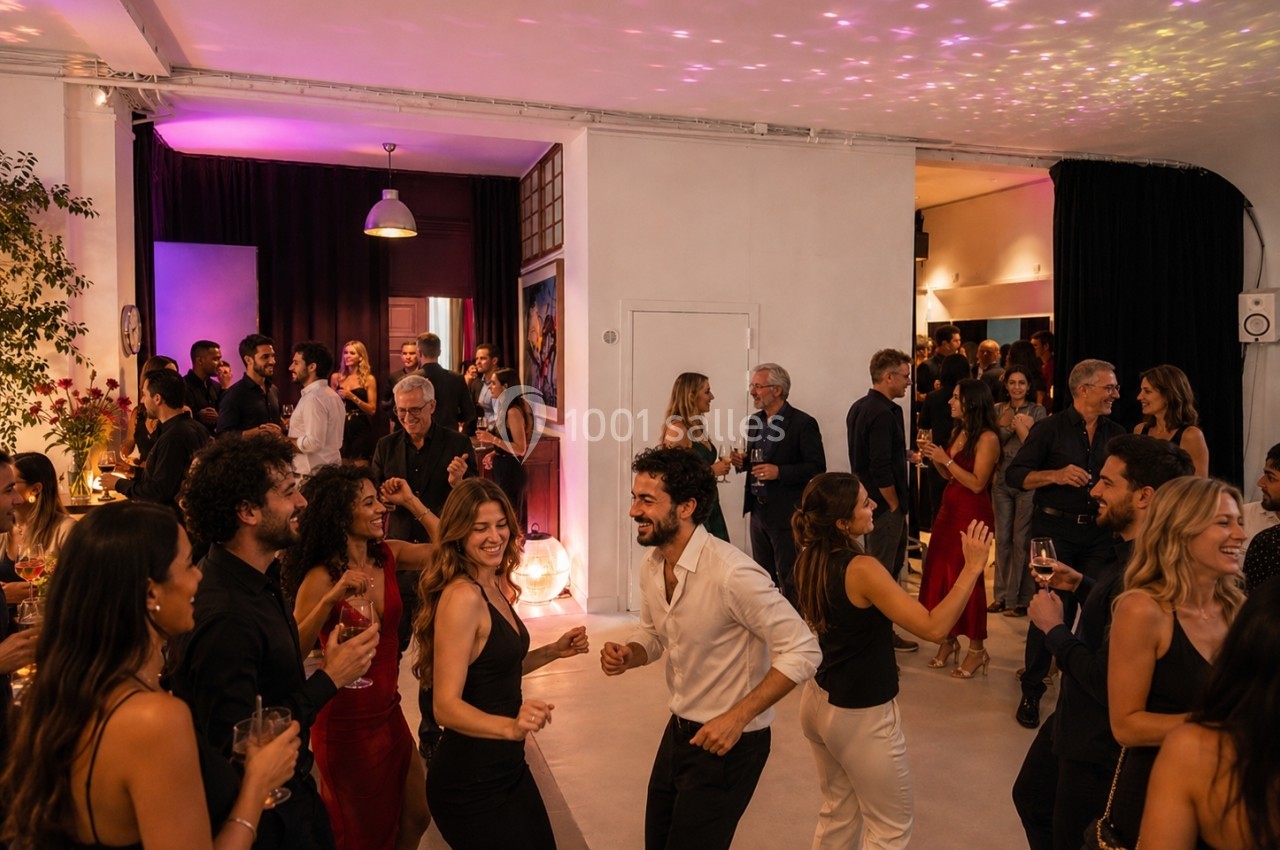 Location salle Paris 20 (Paris) - Studio 7 #28 Des personnes dansent et discutent lors d'une soirée animée dans une salle éclairée par des lumières colorées.