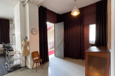 Miniature Location salle Paris 20 (Paris) - Studio 7 #48 Une chaise en bois et un mannequin près d'une porte ouverte donnant sur un couloir lumineux avec une rambarde en fer forgé.
